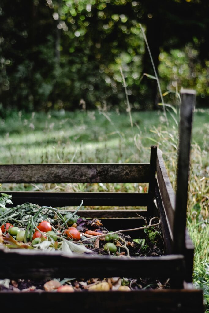 Wooden, organic compost bin with organic waste and vegetables.